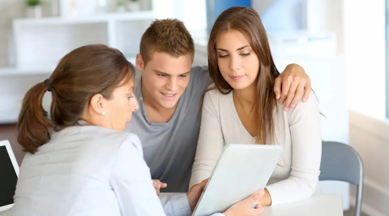 Woman talking to a man and woman while pointing to a tablet.