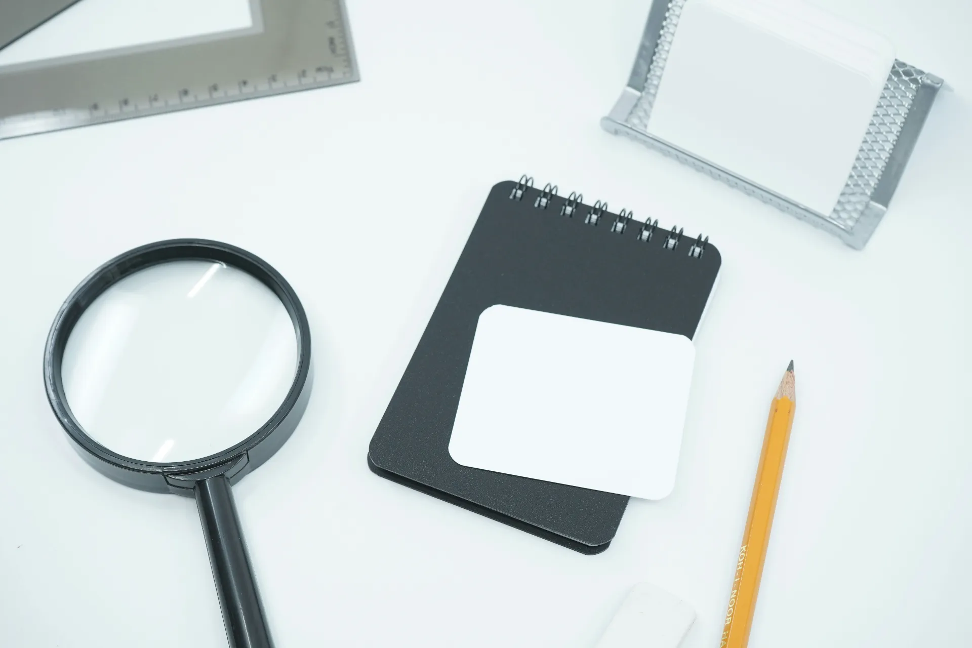 A notebook next to a pencil and a magnifying glass on a desk