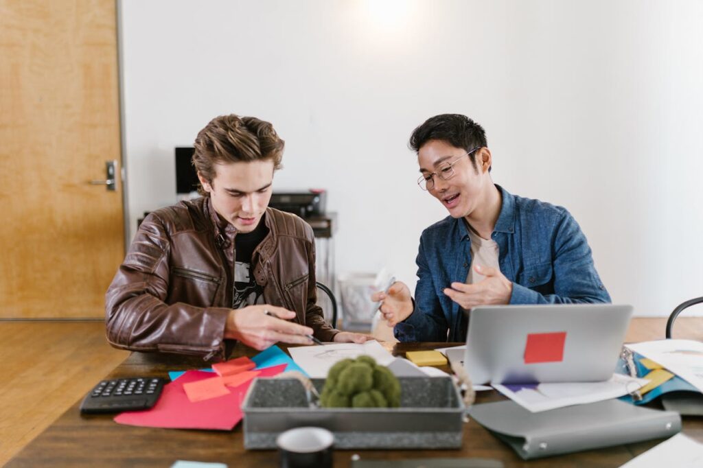 Two people sitting at a desk discussing investing