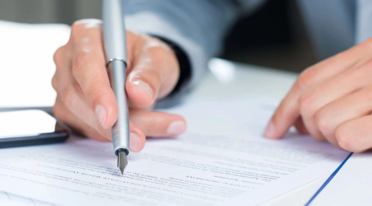 A person using a pen while looking over documents about Vincent Camarda