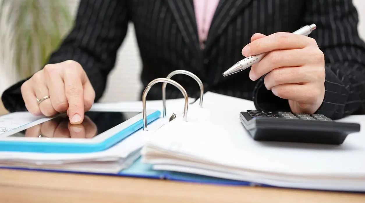 A person touching a tablet while looking over tenants-in-common investment paperwork