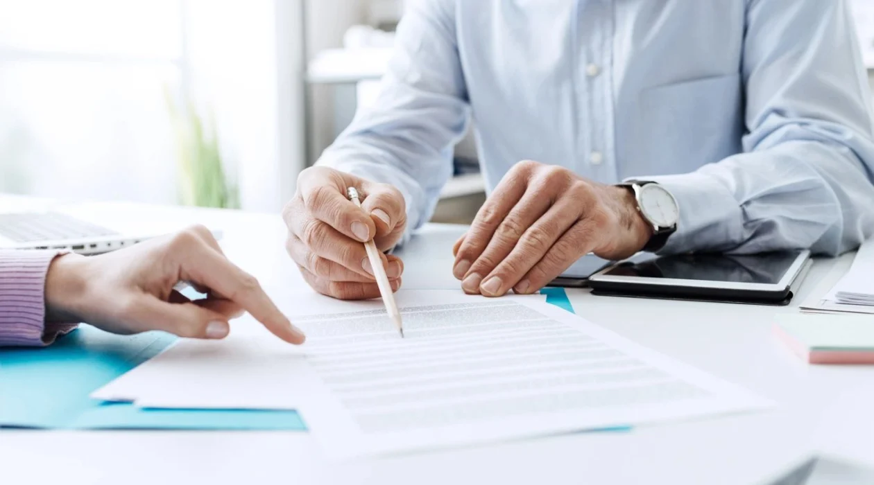 Someone pointing a pencil at part of a document on how to file a FINRA arbitration claim for investment losses